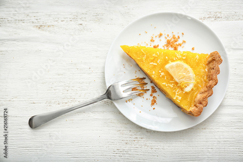 Fototapeta Plate with piece of tasty lemon pie on white wooden table