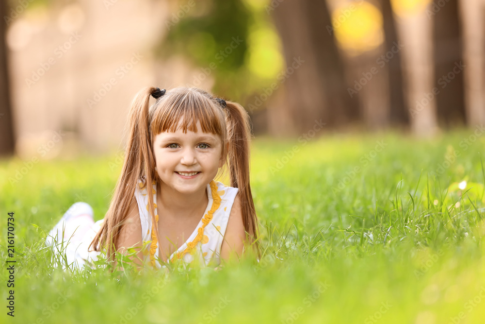 Cute little girl lying on green grass outdoors Cute little girl lying on green grass outdoors
