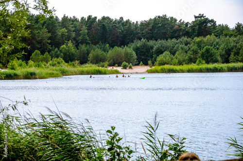 Summer landscape with lake and bathing people