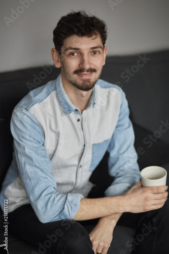 Freelancer resting with a cup of coffee on a couch while thinkin photo