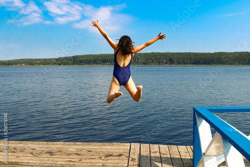 girl jumping into the water from a wooden pier