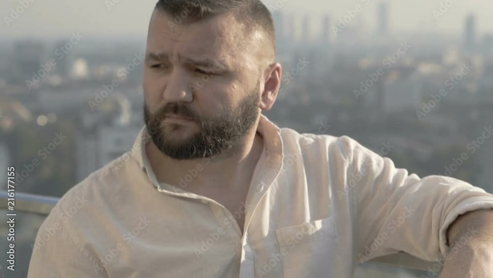Man making toast with a beer to the camera and drinks it on the rooftop
Man making toast with a beer to the camera and drinks it on the rooftop