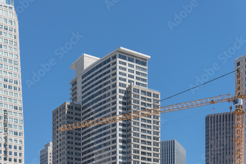 Working yellow crane near completed building in downtown San Francisco  California  USA. Construction and industrial background office and residential skyline  clear blue sky