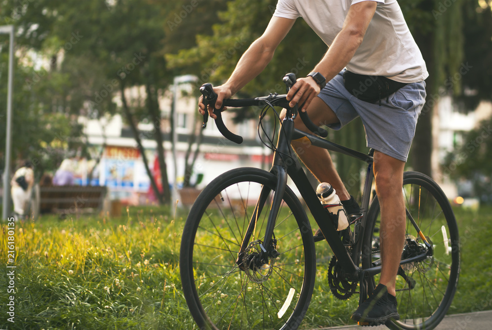 Obraz premium The young guy in casual clothes is cycling on the road in the evening city
