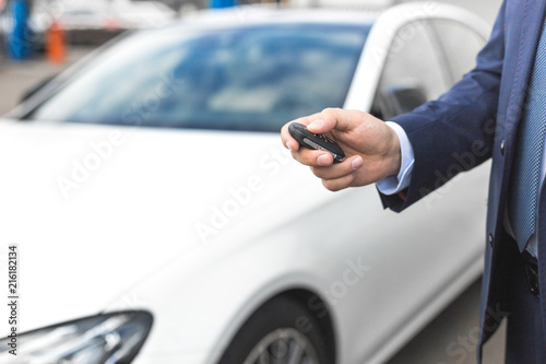 Male holding car keys with car on background