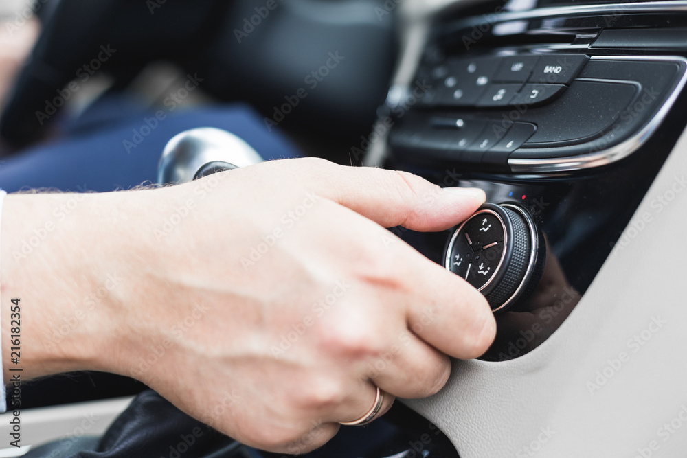 the man presses the buttons in the car in the bright mozannom salon. Adjustment of climate control