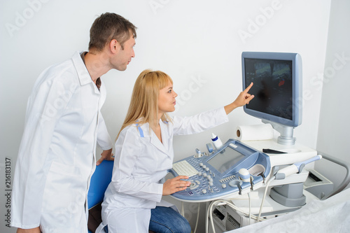 Two doctors looking at the ultrasonography divice