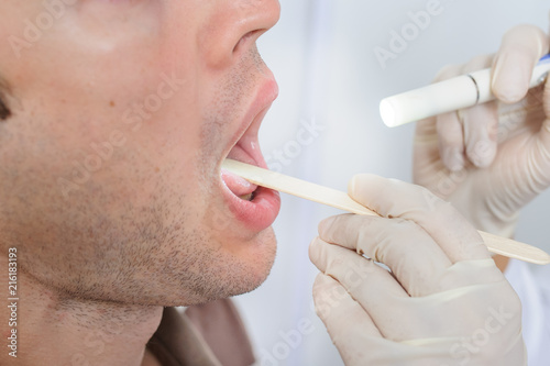 The doctor is looking in the mouth of the patient