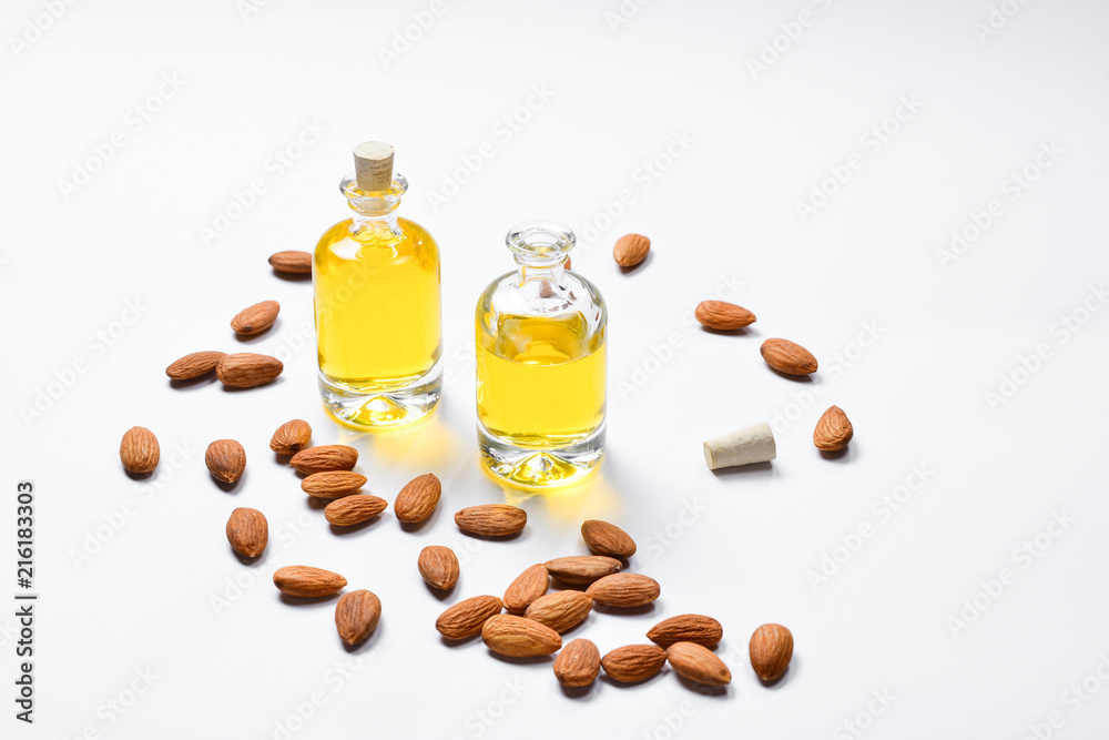 Bottles of almond oil and almonds on white background, copyspace. Bottles of almond oil and almonds on white background, copyspace.