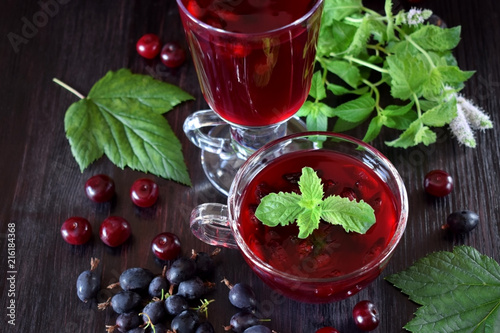 Berry kissel in a glass cup topped with mint against the dark background