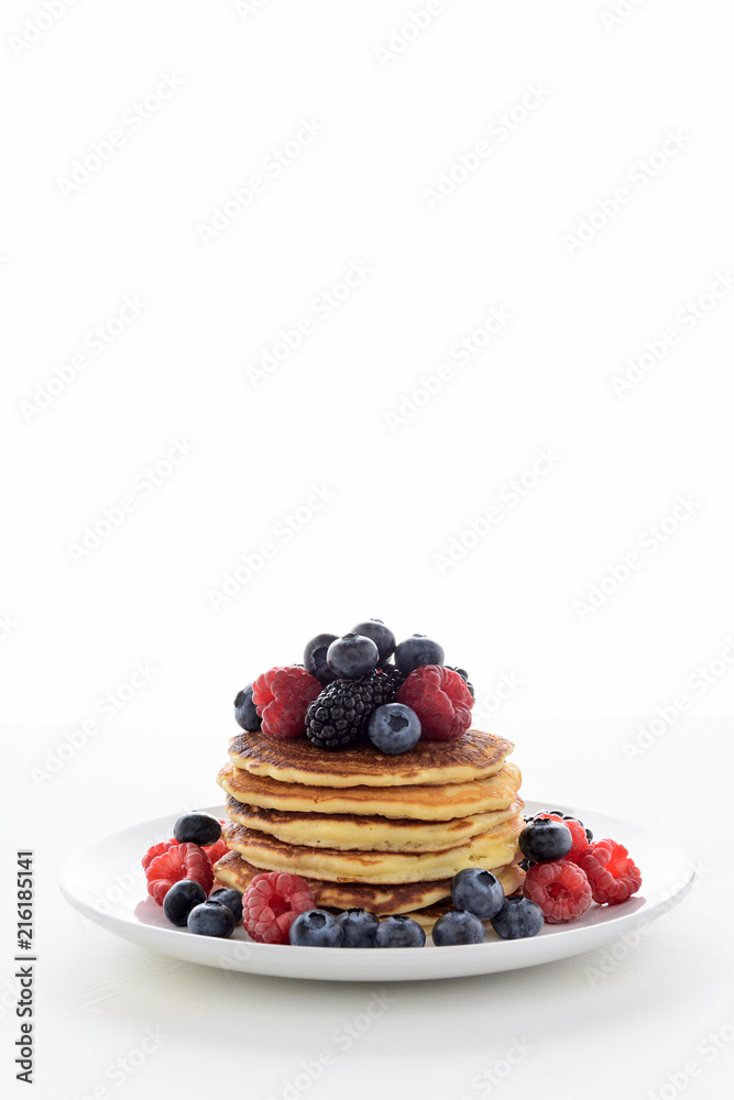 Stack of pancakes with fresh blueberry, raspberry and blackberry on white plate Stack of pancakes with fresh blueberry, raspberry and blackberry on white plate