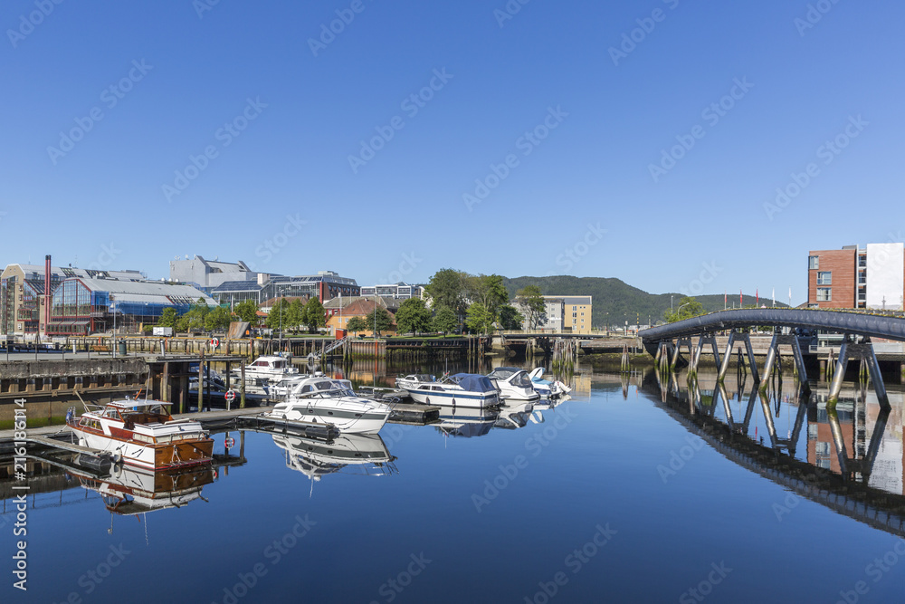 Beautiful cityscape of Trondheim with yachts and pedestrian bridge