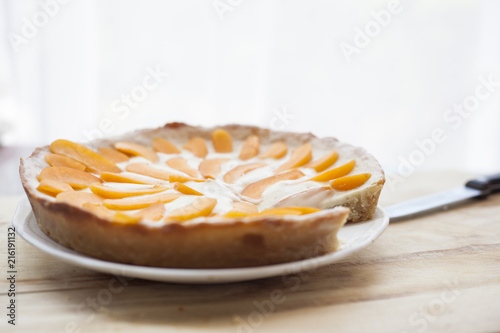Fresh baked and cut lemon apricot pie with crunchy crust doe on a wooden cutting board in bright kitchen