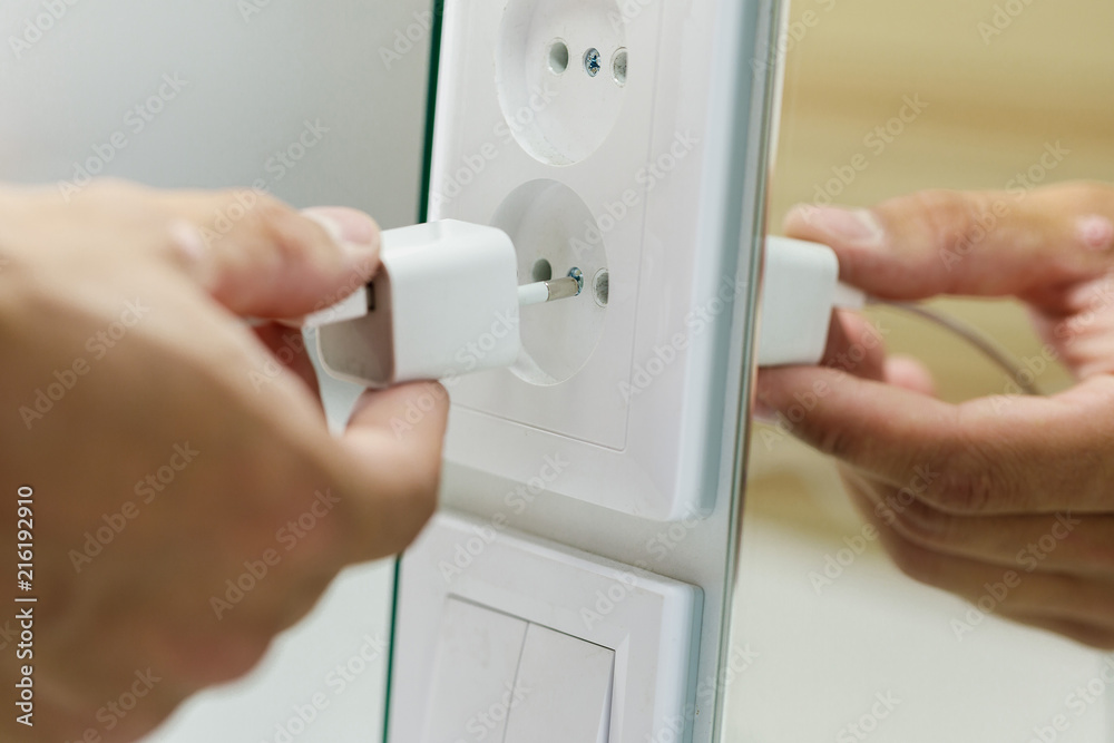 Hand inserting electrical plug into outlet Hand inserting electrical plug into outlet