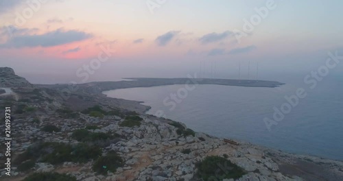 Drone flying over a mountain to unveil the sun rising from the sea in the background early in the morning shot in 4K 60 FPS photo