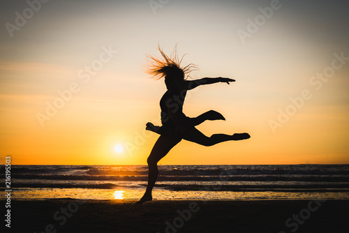 Silhouette of a happy beautiful dancer girl at sunset