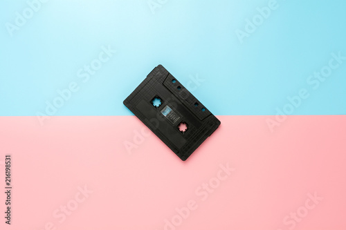 black tape cassette on blue and pink background.