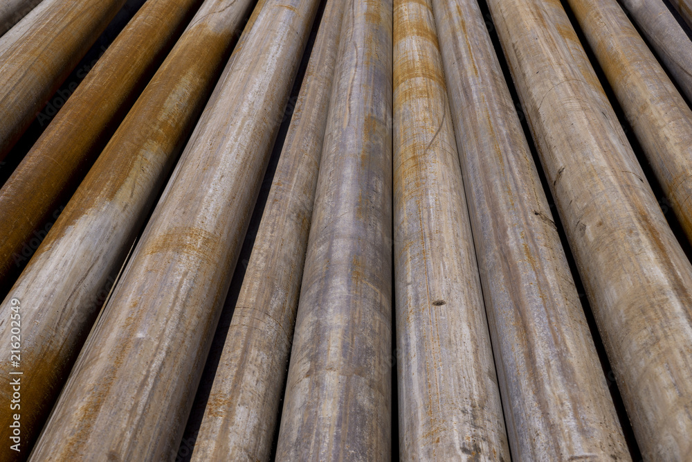 Oil Drill pipe. Rusty drill pipes were drilled in the well section. Downhole drilling rig. Laying the pipe on the deck. View of the shell of drill pipes laid in courtyard of the oil and gas warehouse. Oil Drill pipe. Rusty drill pipes were drilled in the well section. Downhole drilling rig. Laying the pipe on the deck. View of the shell of drill pipes laid in courtyard of the oil and gas warehouse.