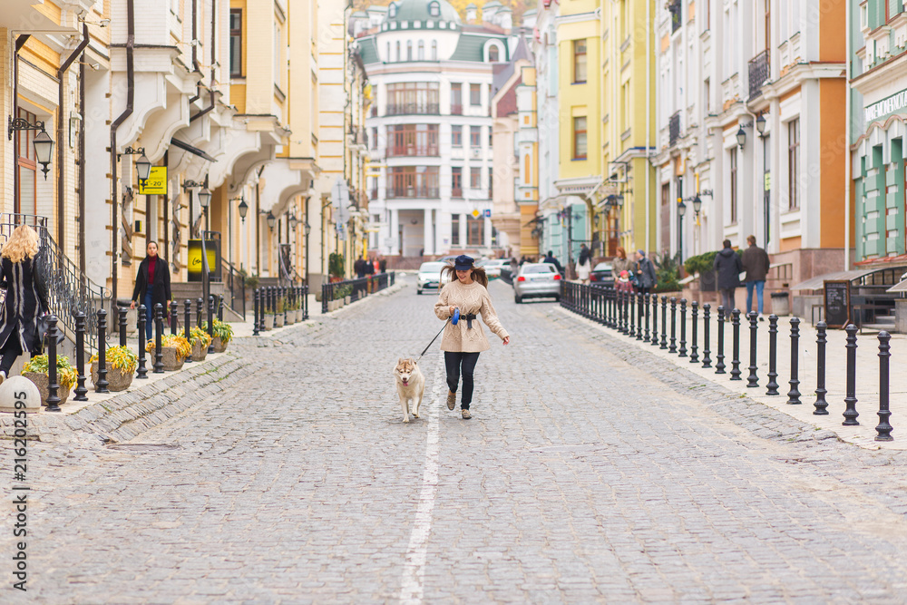 The woman take a walk with husky dog at sunny autumn day on Vozdvizhenka street, Kyiv City, Ukraine