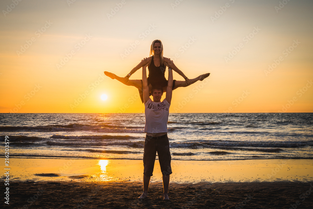 Silhouettes of two dancers doing acrobatics at sunset