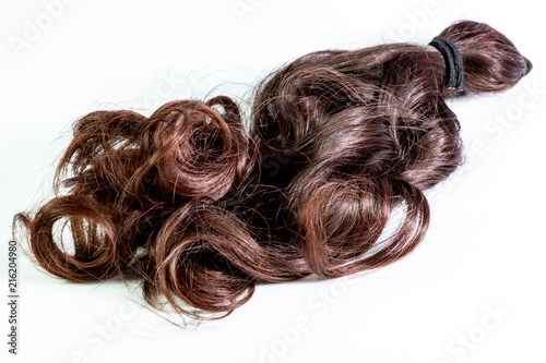 A set of hair extensions of reddish brunette curly hair on a beauty shop table