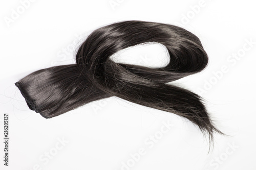 Black long hair extension laying on a white counter waiting to be applied.