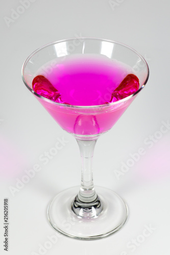 Halloween inspired Pink color cocktail in a clear glass sitting on a white table waiting to be enjoyed.