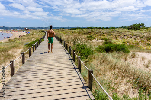 teenager strolls on the catwalks on the beach in Sao Martinho do Porto, Portugal.