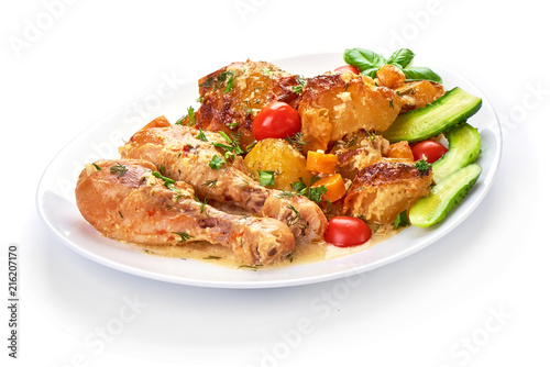 Roasted chicken legs with baked potatoes and vegetables, isolated on white background.