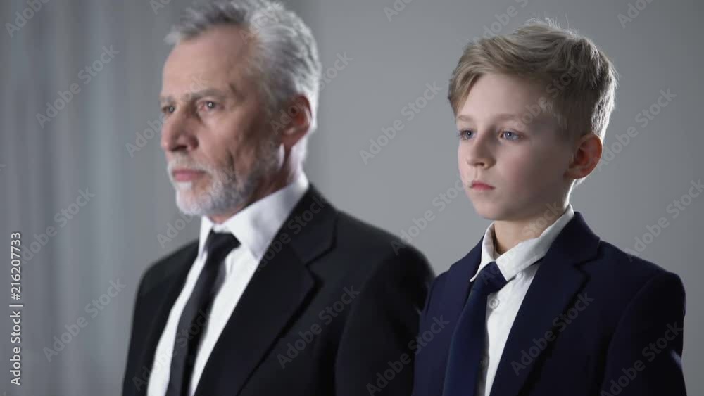 Adult man and little boy in business suits adjusting ties, future successor Adult man and little boy in business suits adjusting ties, future successor
