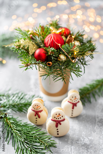 Sweet macaroons in the form of a snowman. Fir branches on a gray background. Merry Christmas card. New year mood