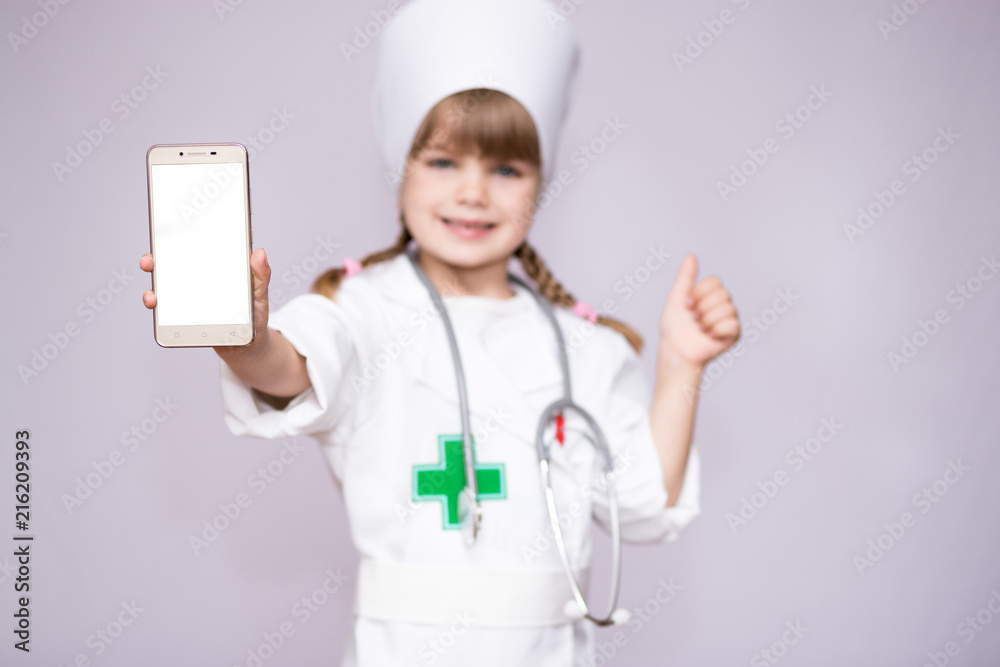 Smiling little girl in medical uniform holding smartphone with blank screen Smiling little girl in medical uniform holding smartphone with blank screen
