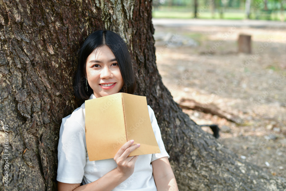 Fototapeta premium Education Concepts. Asian women reading books in the park. Beautiful women are relaxing in the park. Beautiful women are happy to read.