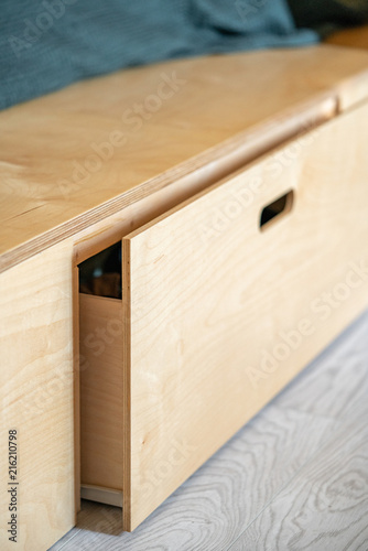 Furniture made of plywood. Retractable floor box, with a hole for the hand. Soft focus and shallow depth of field. Vertically.