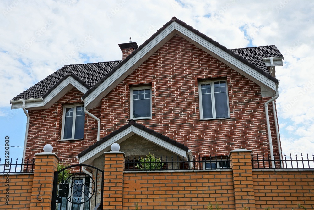 large private brown brick house with windows behind the fence large private brown brick house with windows behind the fence