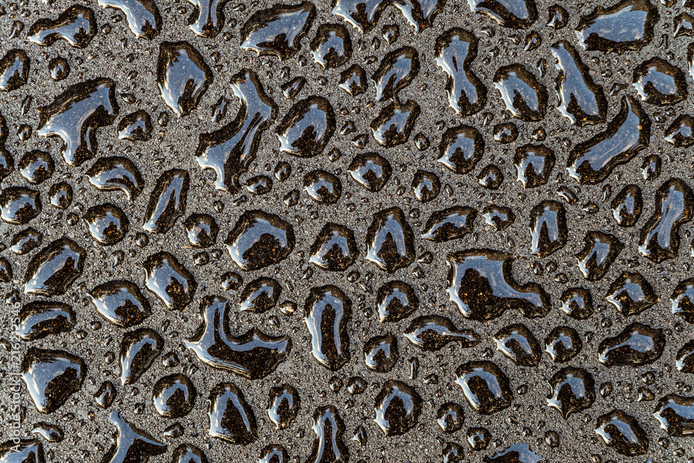 Water drops on a smooth gray surface close-up. Abstract background. Fresh drops of on a dark asphalt. Water drops on a smooth gray surface close-up. Abstract background. Fresh drops of on a dark asphalt.