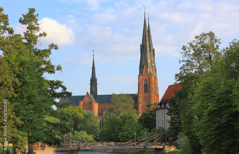 Amazing view on old historical cathedral castle with green trees on front and blue sky on background. Uppsala, Sweden, Europe. Beautiful backgrounds/ wallpapers. 
