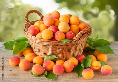 Ripe apricots fruit in a basket on a wooden table.