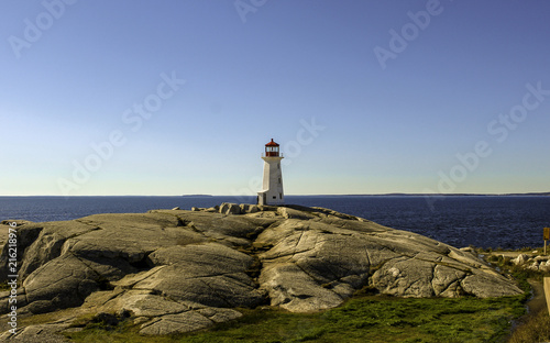 Lighthouse on rocky shores, against blue sky on sunny day, Peggy's Cove, Nova Scotia