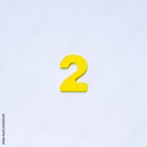 Wooden number 2 with yellow color on white background.