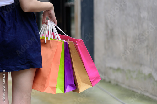 Close-up view asian girl has holding shopping colorful bags with shopping mall and building background.