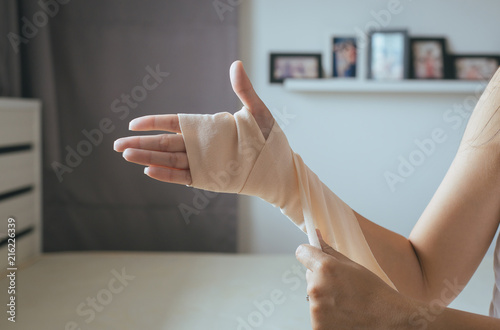 Leinwand Poster Woman using elastic bandage with hand,Female putting bandage on his injured hand