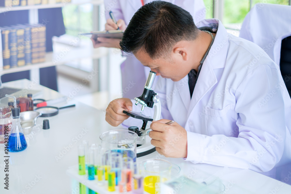 Asian Male doctors or scientist using microscope to study and research on the biology at the Science Laboratory.Concept Science and Medical image. Asian Male doctors or scientist using microscope to study and research on the biology at the Science Laboratory.Concept Science and Medical image.