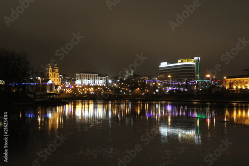 view of the night city lit by lights on the other side of the river © Kseniya