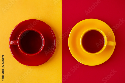Tea in cups on different backgrounds. Yellow and red cups of tea pairs on yellow and red backgrounds. View from above. Contrast of different colors. photo