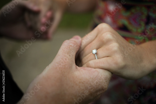 Bild auf Leinwand "She said yes" - Newly engaged young couple holding hands displaying diamond eng