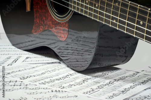 dark acoustic guitar on a background sheet notes, close-up