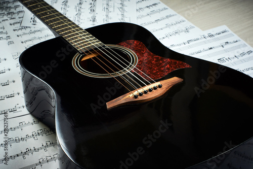 dark acoustic guitar on a background sheet notes, close-up