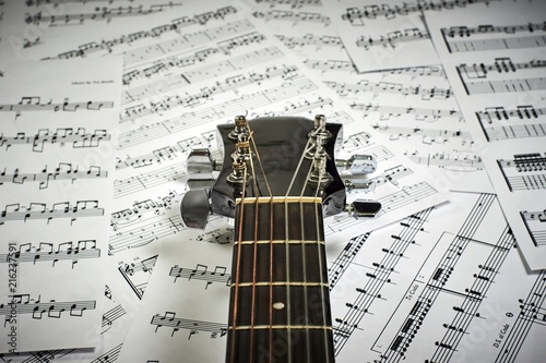 fingerboard acoustic guitar on the background of sheet with notes, close-up