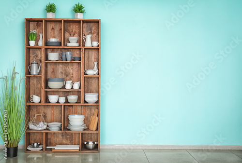 Kitchen shelving with dishes on color wall background photo
